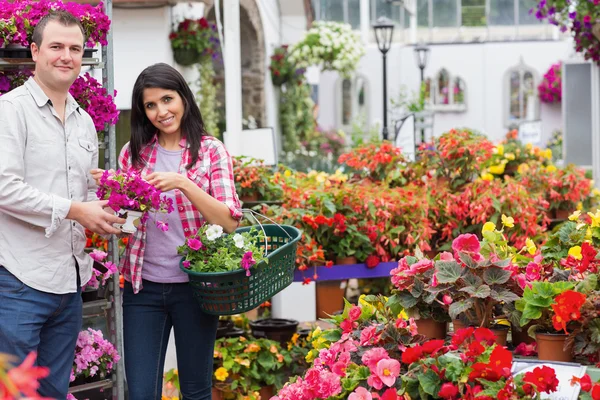 Coppia sorridente che tiene cesto e bouquet — Foto Stock