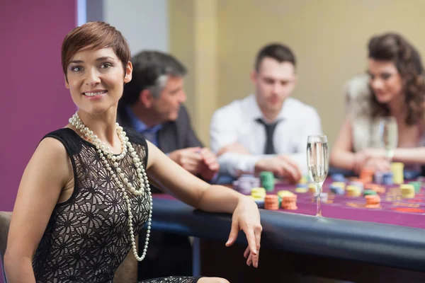 Smiling woman taking break from roulette with champagne — Stock Photo, Image