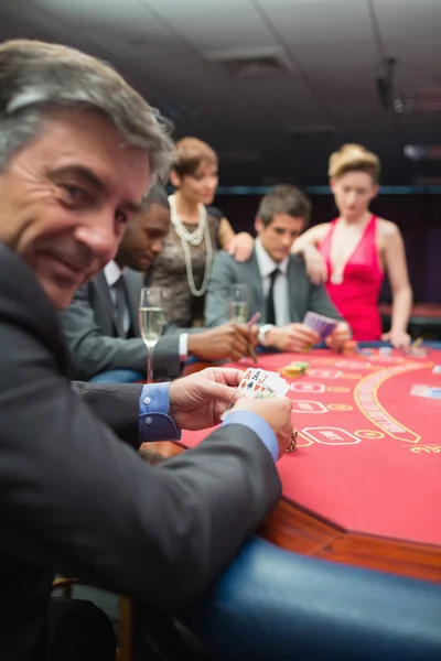 Smiling man looking up from poker game — Stock Photo, Image