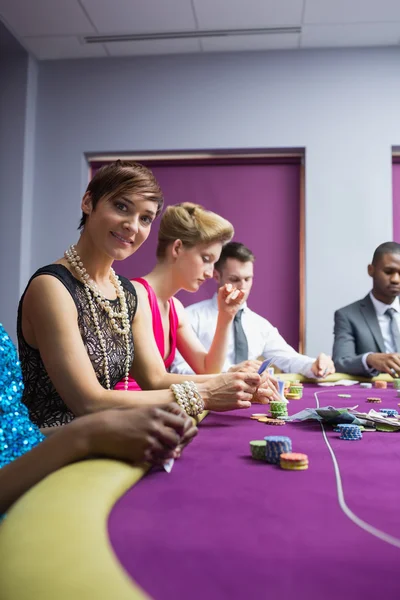 Kvinnan ler sitter vid pokerbordet — Stockfoto