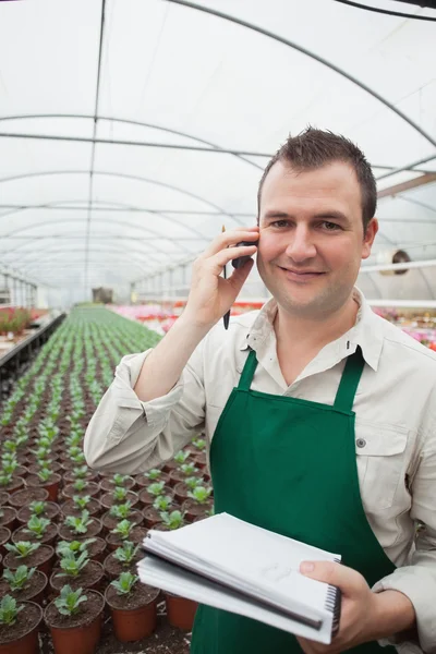 Worker taking notes and calling in greenhouse — Stock Photo, Image