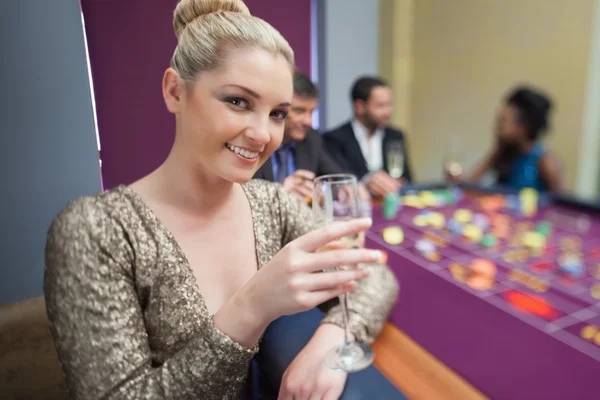 Rubia levantando copa de champán en la mesa de ruleta — Foto de Stock