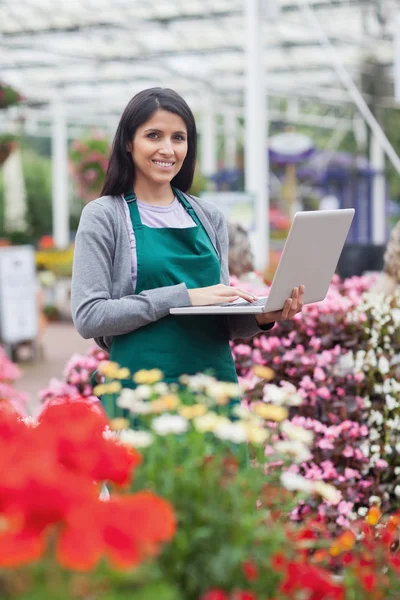 Brünette tippt auf dem Laptop im Gartencenter — Stockfoto