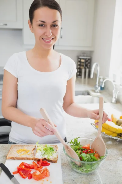Junge Frau wirft Salat für Sandwich — Stockfoto