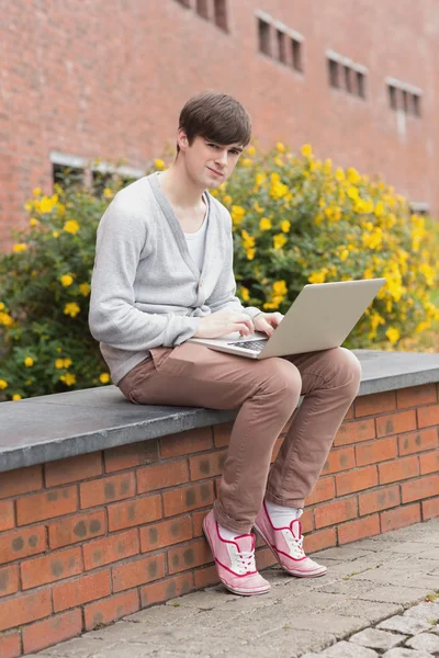 Student zittend op de muur met laptop — Stockfoto