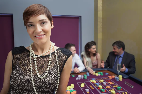 Femme souriante et debout à la table de roulette — Photo