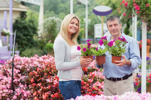 Couple holding flowers in garden center — Stock Photo, Image