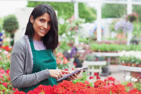 Funcionário sorrindo usando tablet pc para verificar flores — Fotografia de Stock