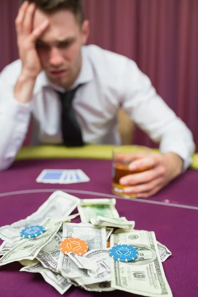 Uomo con bicchiere di whisky appoggiato sul tavolo da poker nel casinò — Foto Stock