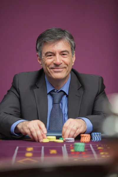 Hombre sonriente jugando a la ruleta en un casino — Foto de Stock