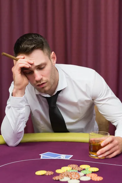 Mann lehnt an Pokertisch und hält Zigarre — Stockfoto