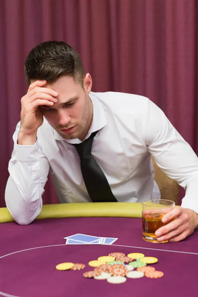 Hombre sosteniendo vaso de whisky en la mesa de poker — Foto de Stock