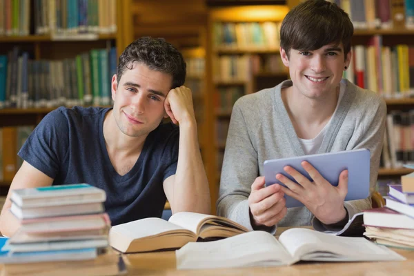 Young men looking up from studying in library — Stock Photo, Image
