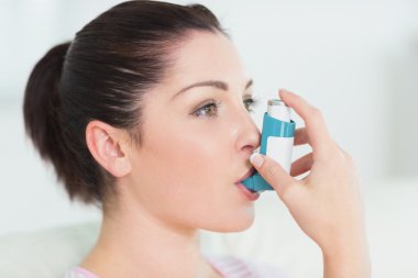 Woman using an asthma inhaler clipart