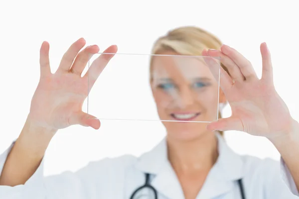Doctor holding up clear pane and smiling — Stock Photo, Image