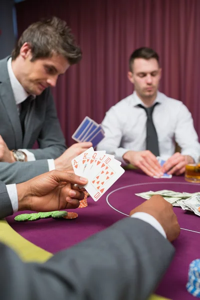 Человек за покерным столом имеет королевский флеш — стоковое фото