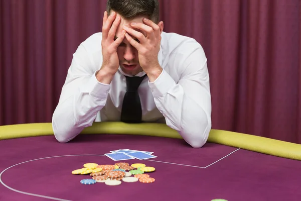 Man håller huvudet i händerna vid pokerbordet — Stockfoto