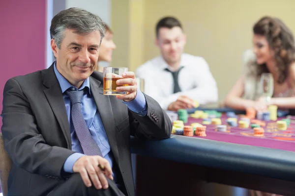 Uomo che beve whisky al tavolo della roulette — Foto Stock