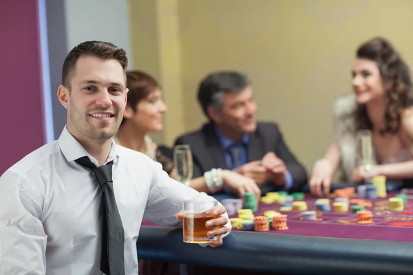 Joven con whisky mirando desde la mesa de ruleta — Foto de Stock