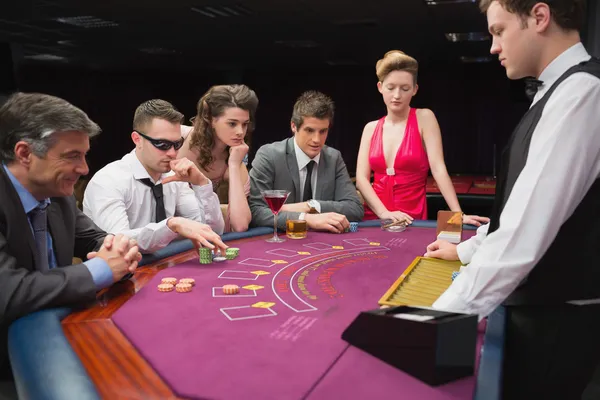 Sentado en la mesa jugando al poker — Foto de Stock