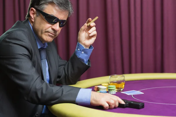 Man with gun at poker table — Stock Photo, Image