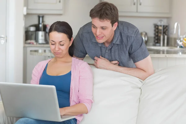 Mujer usando portátil con el hombre mirando en — Foto de Stock