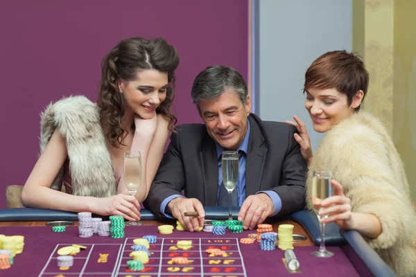 Człowiek i dwie kobiety rozmowy przy stole ruletki — Zdjęcie stockowe