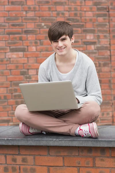 Man zit op de muur met laptop — Stockfoto