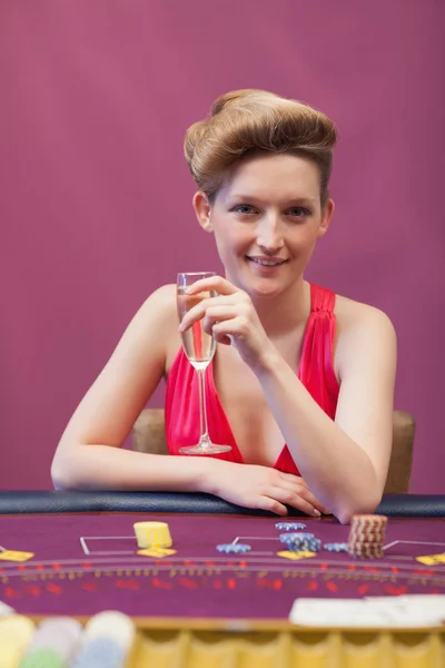 Woman sitting at table while holding a glass of champagne — Stock Photo, Image