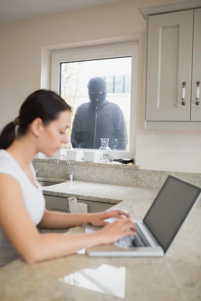 Robber observant une jeune femme dans la cuisine — Photo