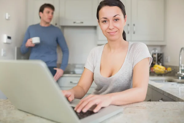 Jovem mulher usando laptop com homem bebendo café — Fotografia de Stock