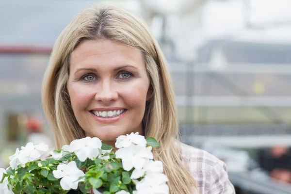 Loira sorridente segurando flores brancas — Fotografia de Stock