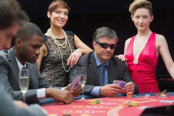 Man in sunglasses playing poker with two women either side — Stock Photo, Image