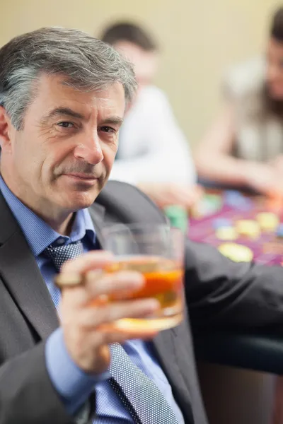 在轮盘赌桌升降玻璃的威士忌酒的男人 — 图库照片