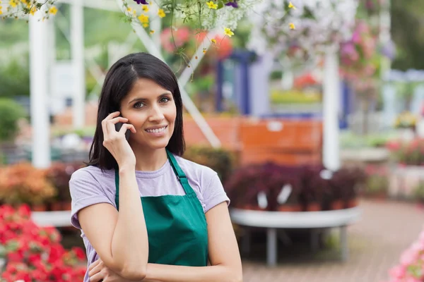 Mujer trabajando en el centro de jardinería haciendo una llamada —  Fotos de Stock