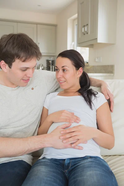 Femme enceinte assise sur le canapé avec son partenaire — Photo