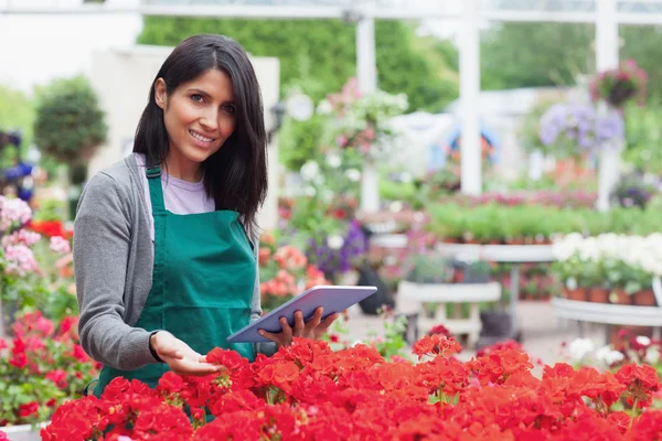 Mitarbeiterin wählt Blumen mit Tablet-PC im Gartencenter aus — Stockfoto