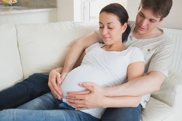 Padres embarazadas relajándose en el sofá — Foto de Stock