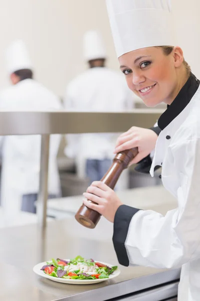 Chef adicionando pimenta à salada — Fotografia de Stock