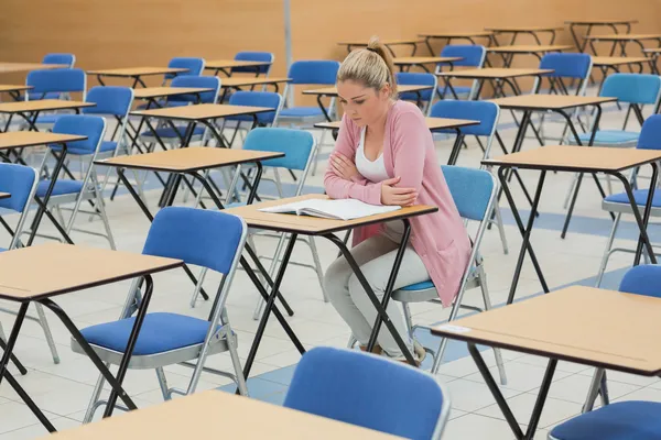 Student studying at desk in empty exam hall