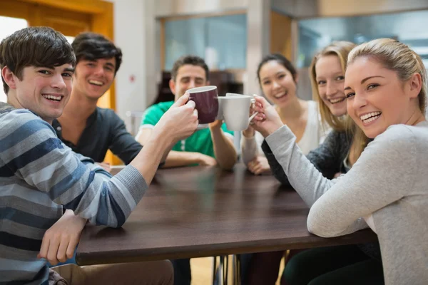 Students sitting clinking cups — Stock Photo, Image