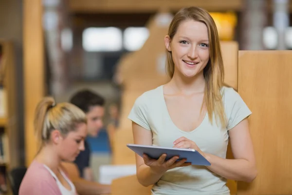 Vrouw staande houden een tabletcomputer terwijl glimlachen — Stockfoto