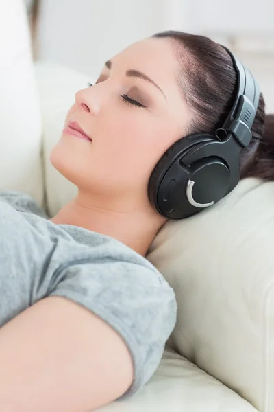 Jeune femme allongée sur le canapé et écoutant de la musique — Photo