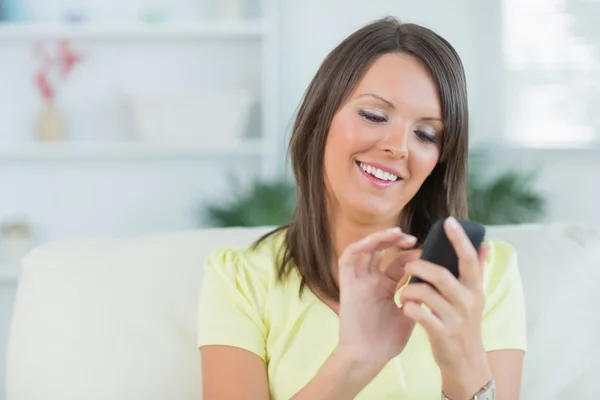 Mulher enviando mensagens com seu smartphone na sala de estar — Fotografia de Stock
