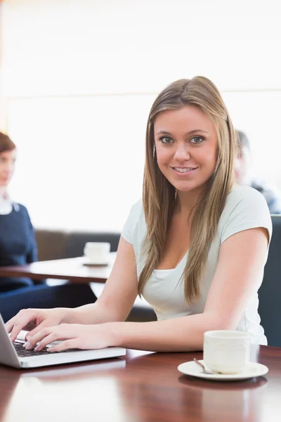 Studentin sitzt lächelnd mit Laptop im Café — Stockfoto
