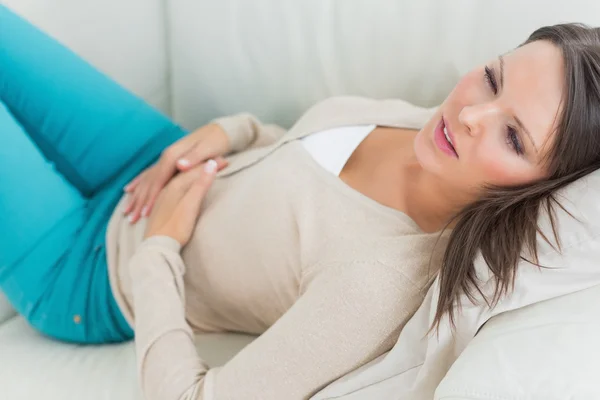 Mujer enferma acostada en un sofá con dolor de estómago — Foto de Stock