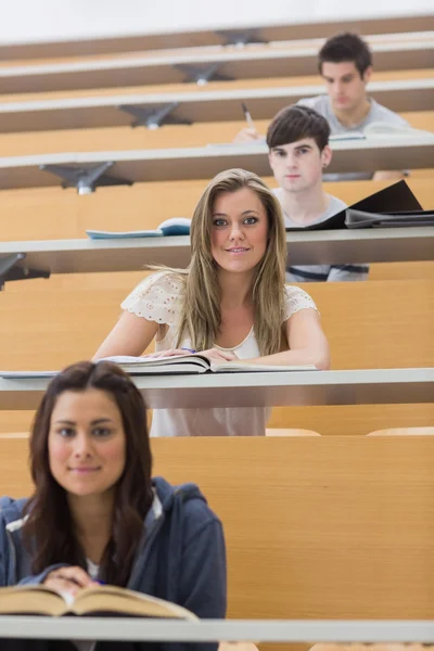 Uczniowie siedzący uśmiechający się w sali wykładowej — Zdjęcie stockowe