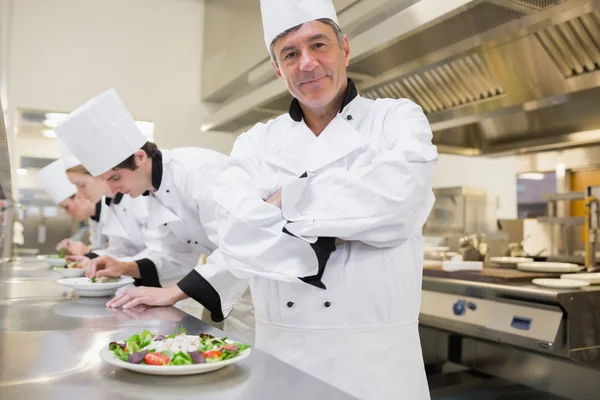 Chef sonriendo con otros preparando ensaladas — Foto de Stock