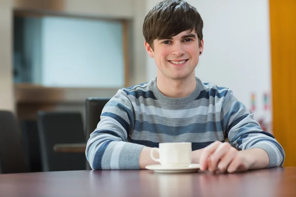 Student sitter vid bord dricker kaffe i college café — Stockfoto
