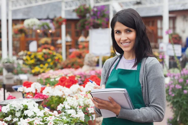 Medarbetare att göra anteckningar på blommorna i garden center Royaltyfria Stockfoton